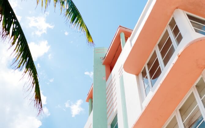 photo of a house taken from the ground looking up, the house is white and orande and there are leaves from a palm tree coming into the left of the frame